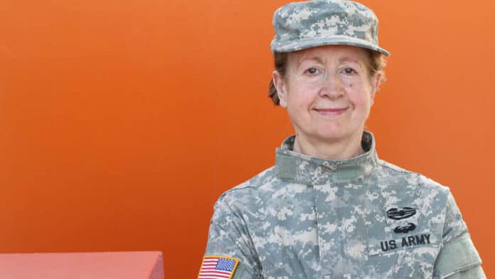 Female Army veteran standing against an orange background